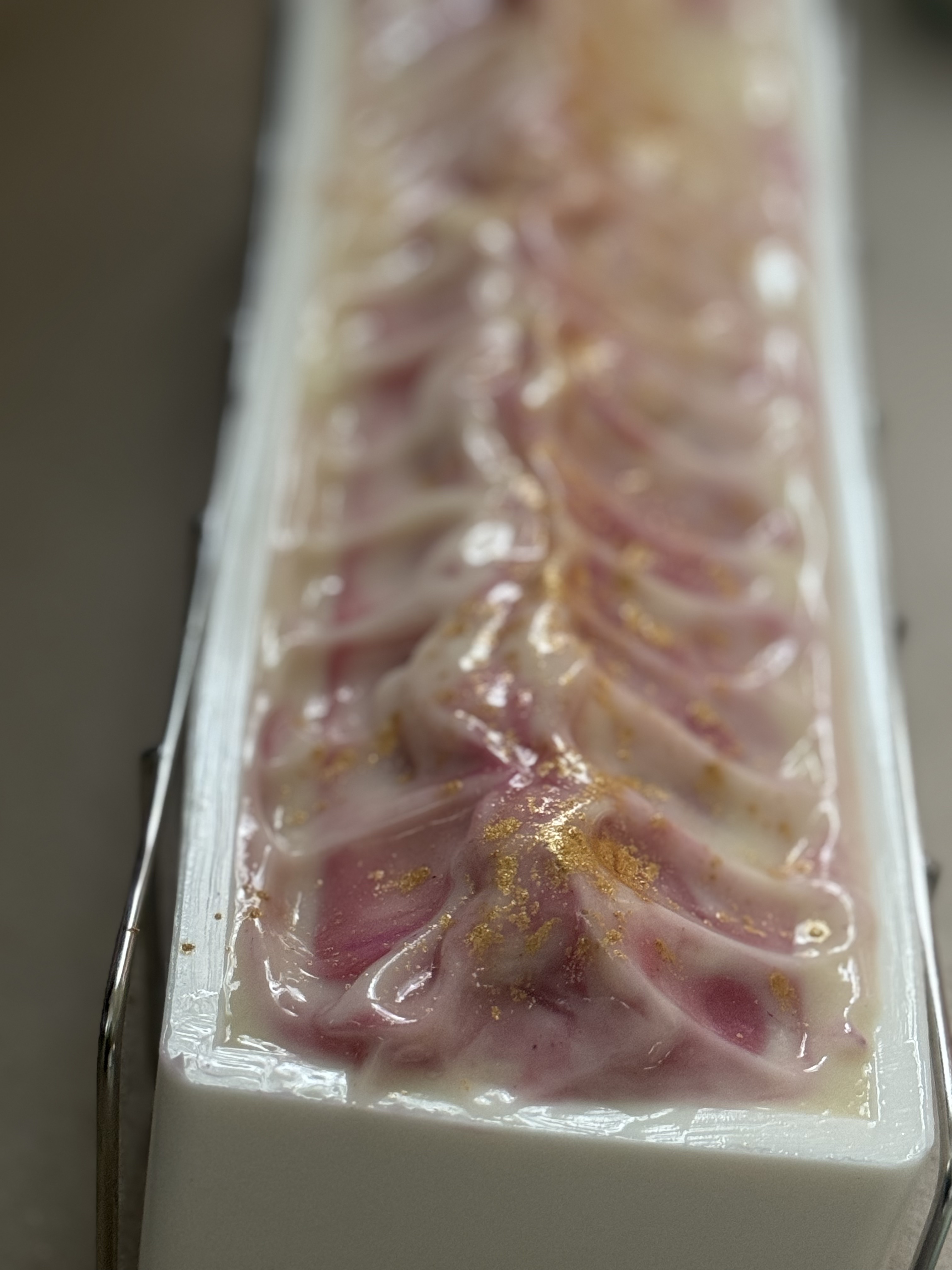 Four artisan cold process soap bars arranged on a wood surface showing beautiful swirl patterns in blue, green, and purple and pink.